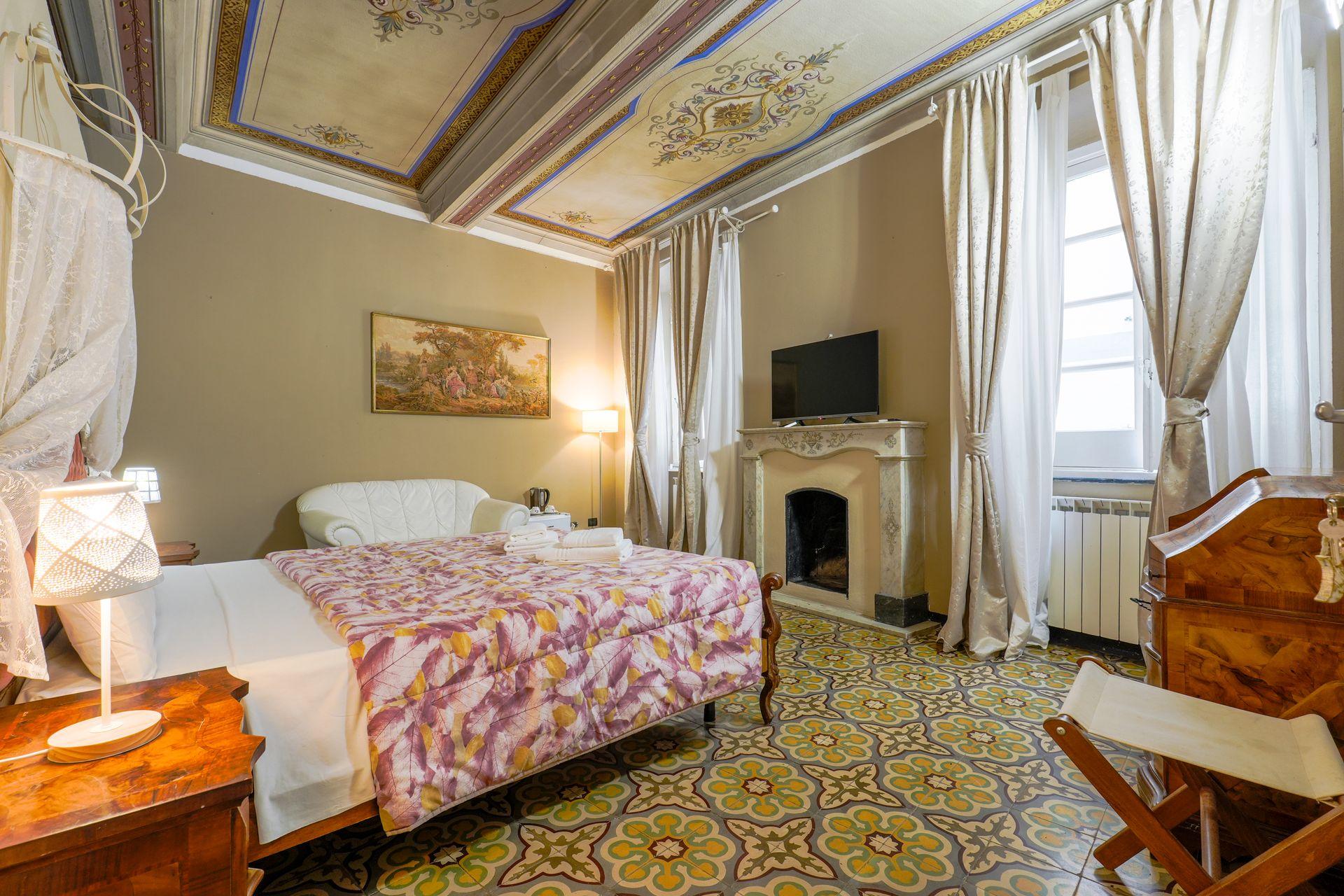 Elegant bedroom with ornate ceiling, floral bedspread, vintage furniture, and a fireplace.