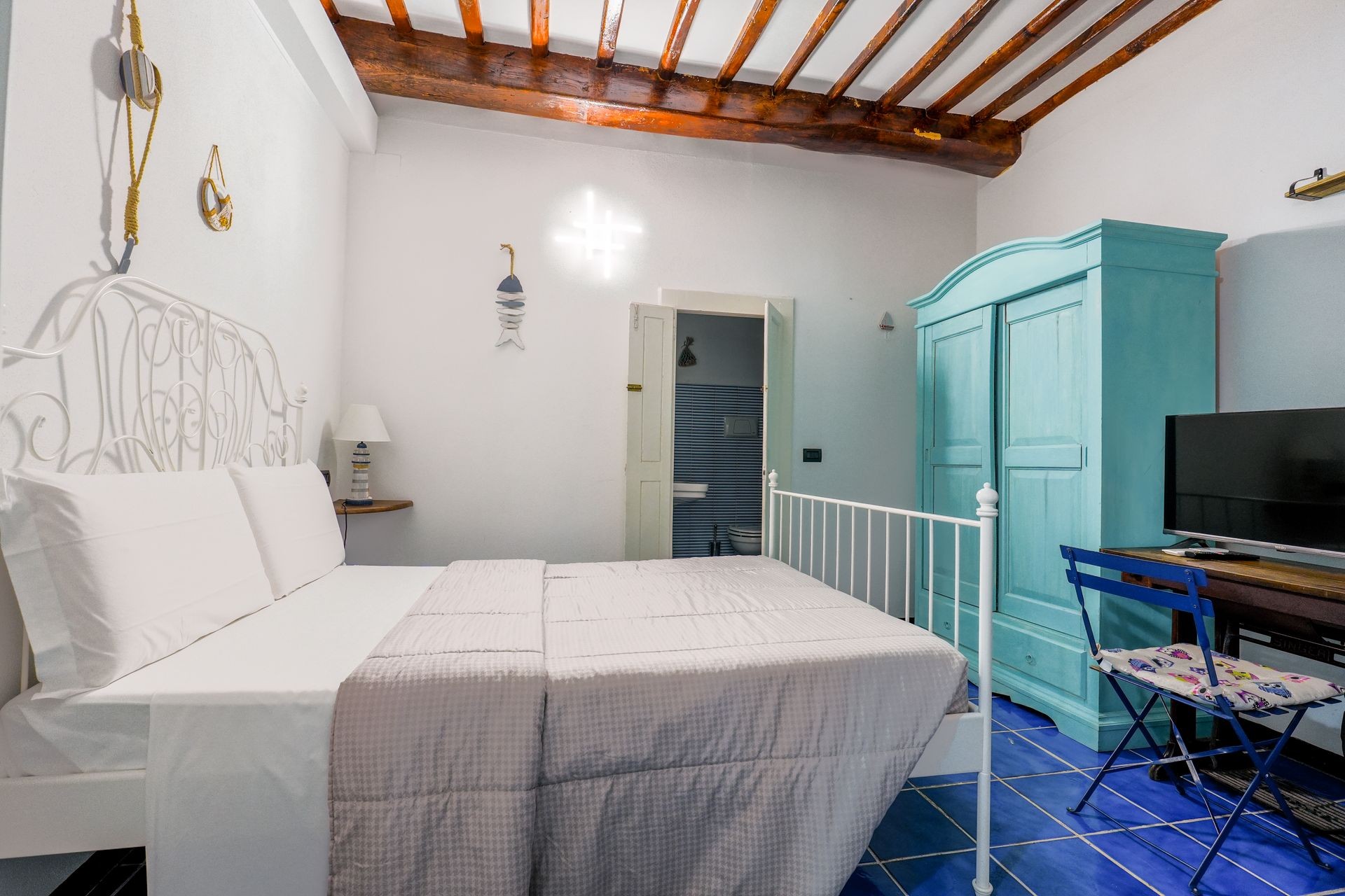 Cozy bedroom with white bed, turquoise wardrobe, and striped wall decorations.